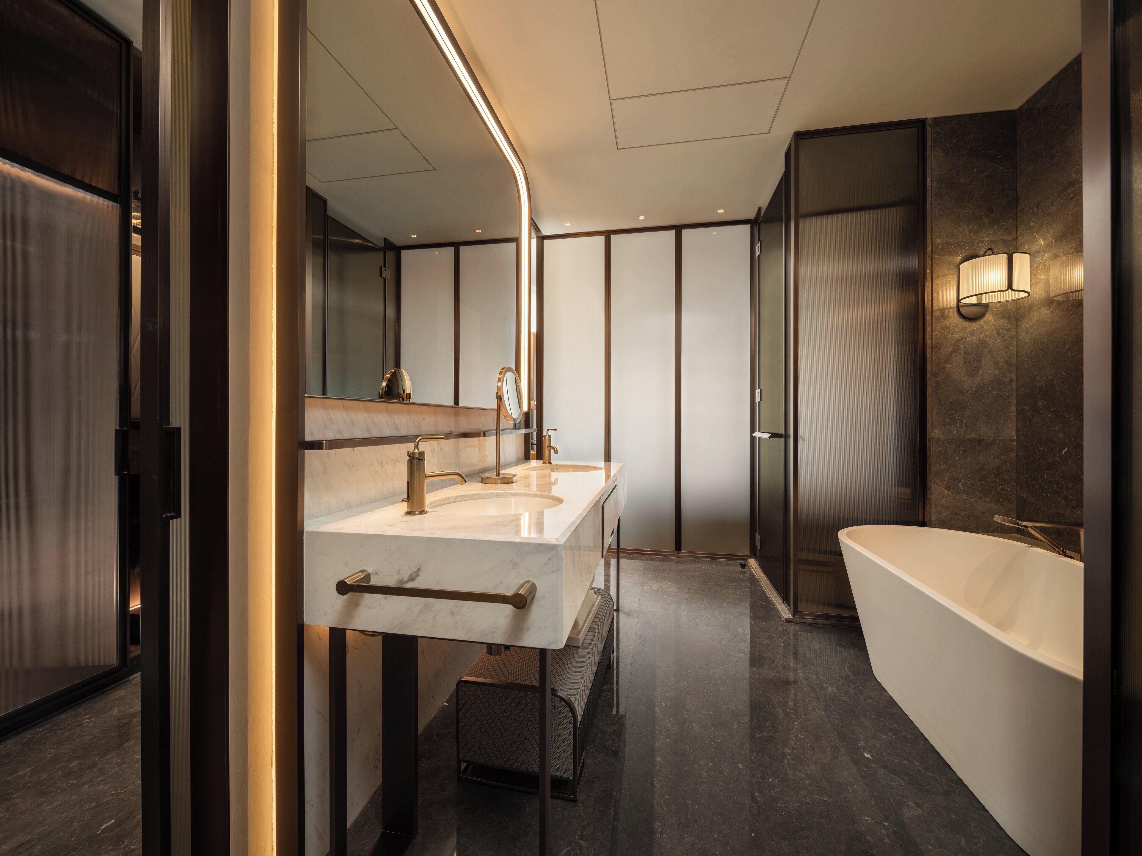 Un baño moderno con una bañera amplia, dos lavamanos y un espejo.
