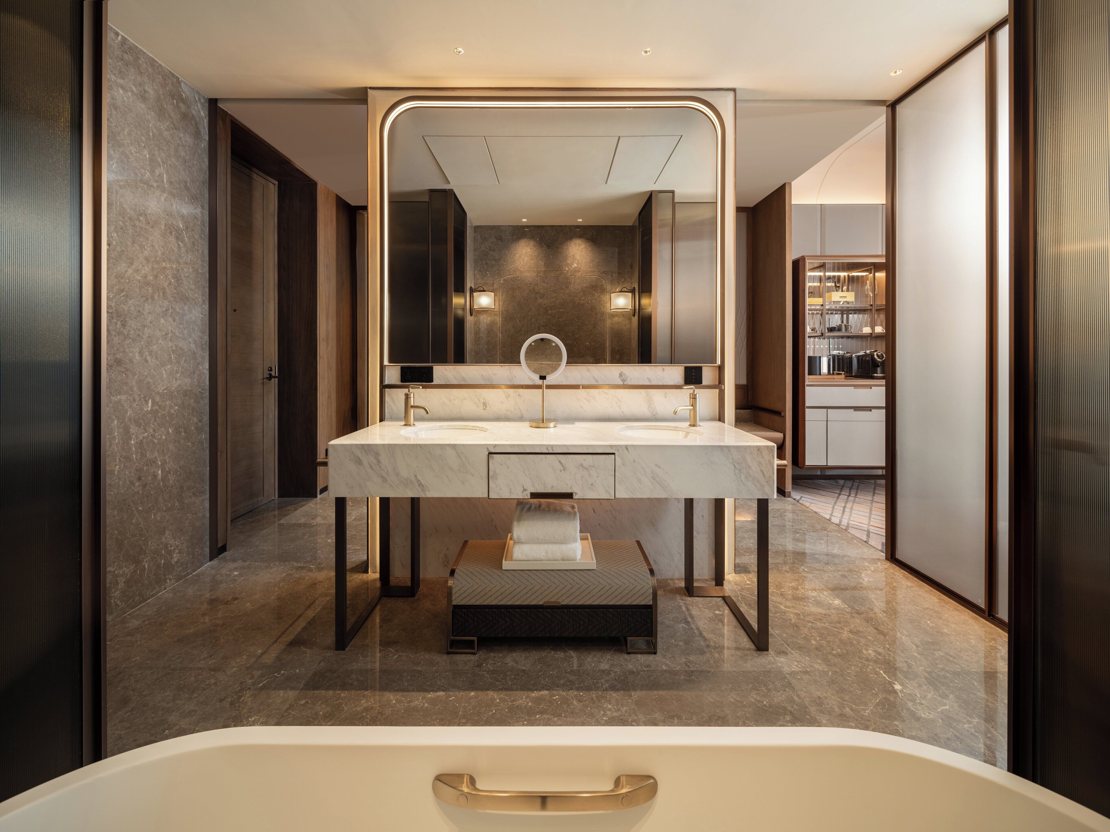 A modern bathroom with a large mirror, a marble sink, and a bathtub.
