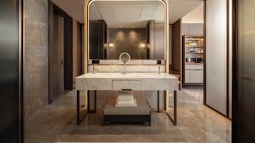 A modern bathroom with a large mirror, a marble sink, and a bathtub.