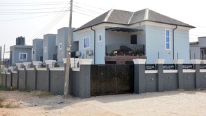 A modern two-story house with a grey facade, a black gate, and a paved driveway. - HABBOT LUXURY APARTMENT  (Ibadan)