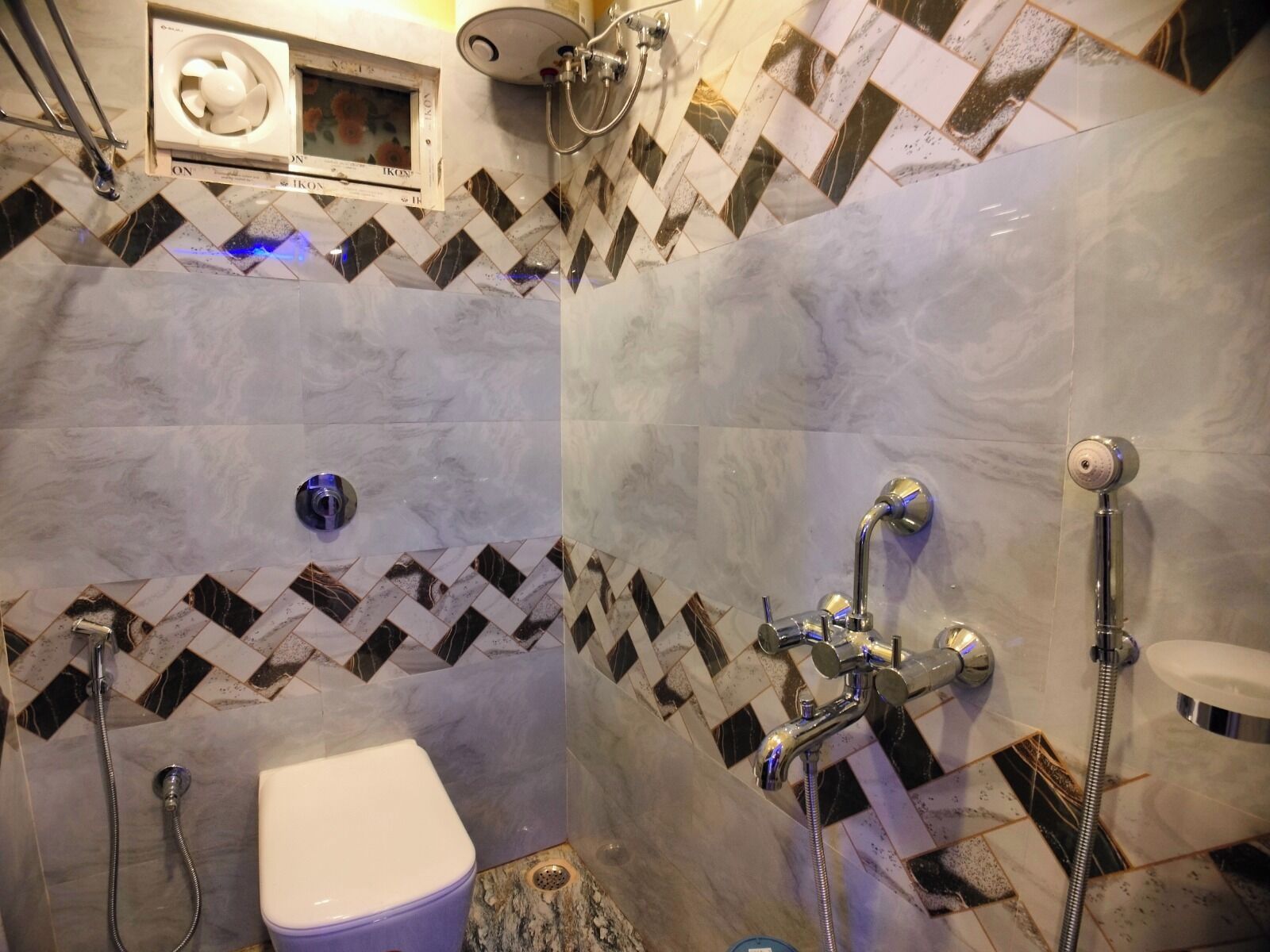 Un baño con ducha, inodoro y un ventilador de pared.