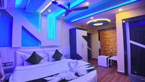 A modern hotel room with a large bed, a ceiling fan, and a wall-mounted TV. - The Pelican Beach Resort Mandarmoni (Kanthi)