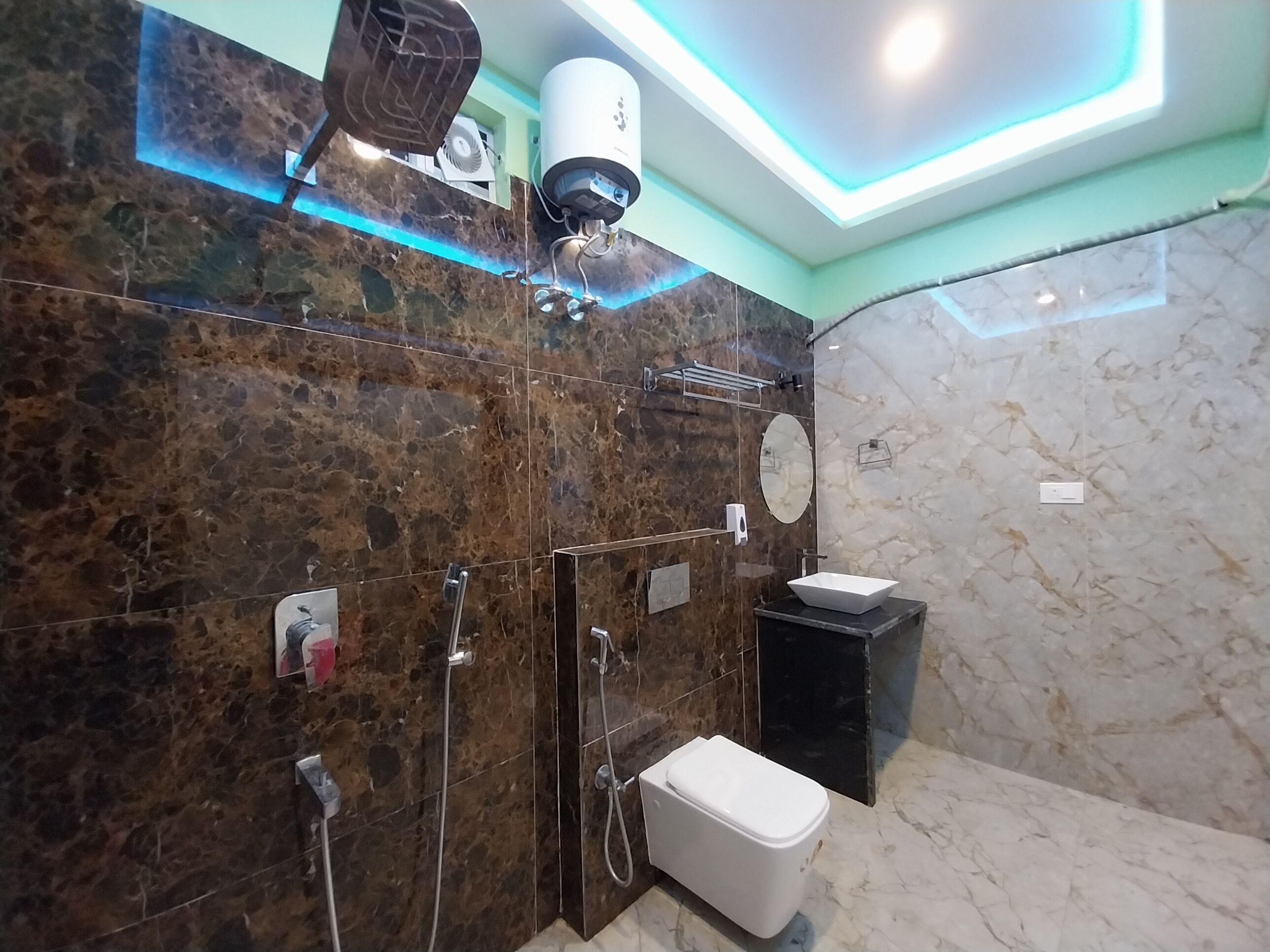 A modern bathroom with a marble wall, a white sink, and a toilet.