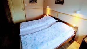 Et hotelværelse med seng, sengeborde med lamper, en aircondition og to billeder i rammer på væggen.