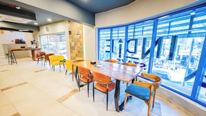 A spacious meeting room with a large table and chairs, a kitchen area, and large windows with a view of the city. - Indie Stays Studios (Mumbai)