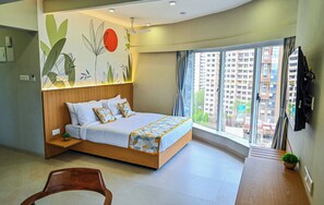 A modern bedroom with a wooden bed, a large window, and a wall mural. - Indie Stays Studios (Mumbai)