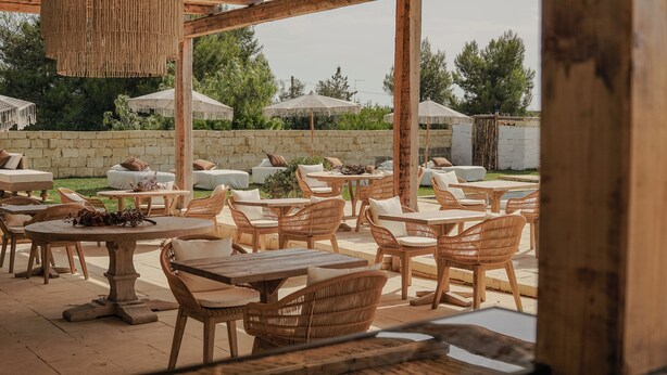 An outdoor patio with wicker furniture, stone walls, and umbrellas. - Borgo Bevagna Relais (Manduria)