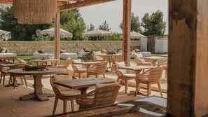 Un patio al aire libre con mobiliario de mimbre, paredes de piedra y sombrillas.