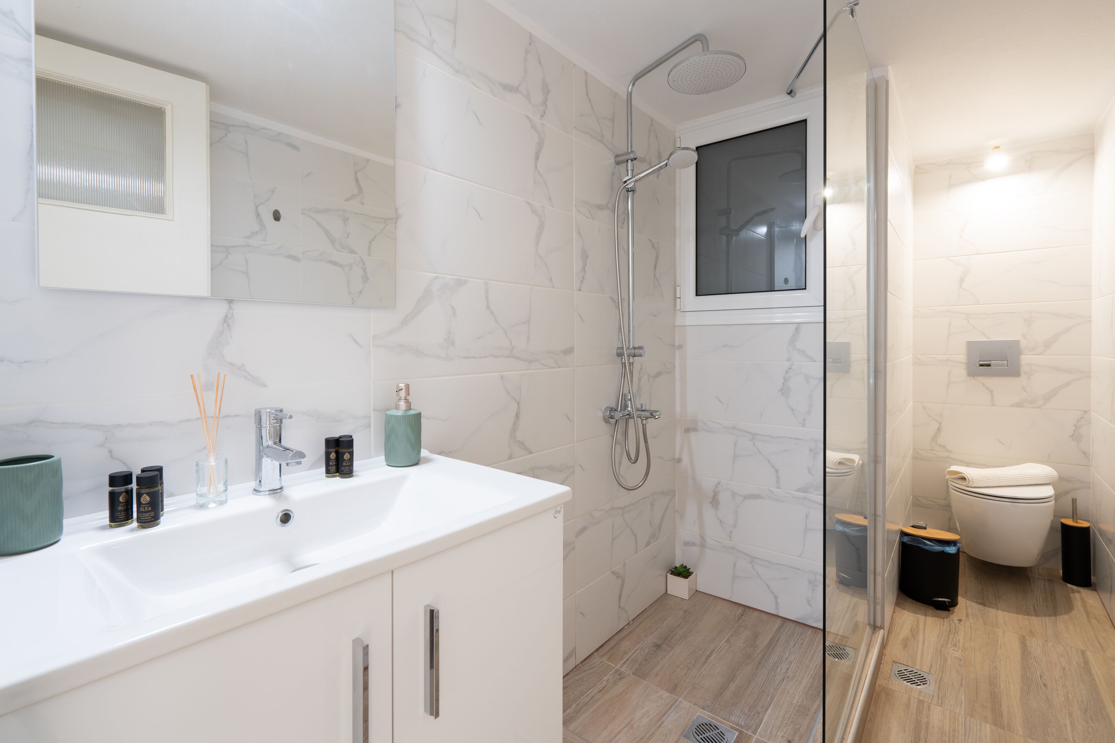 Un bagno moderno con un lavabo in marmo bianco, un box doccia in vetro e un water.