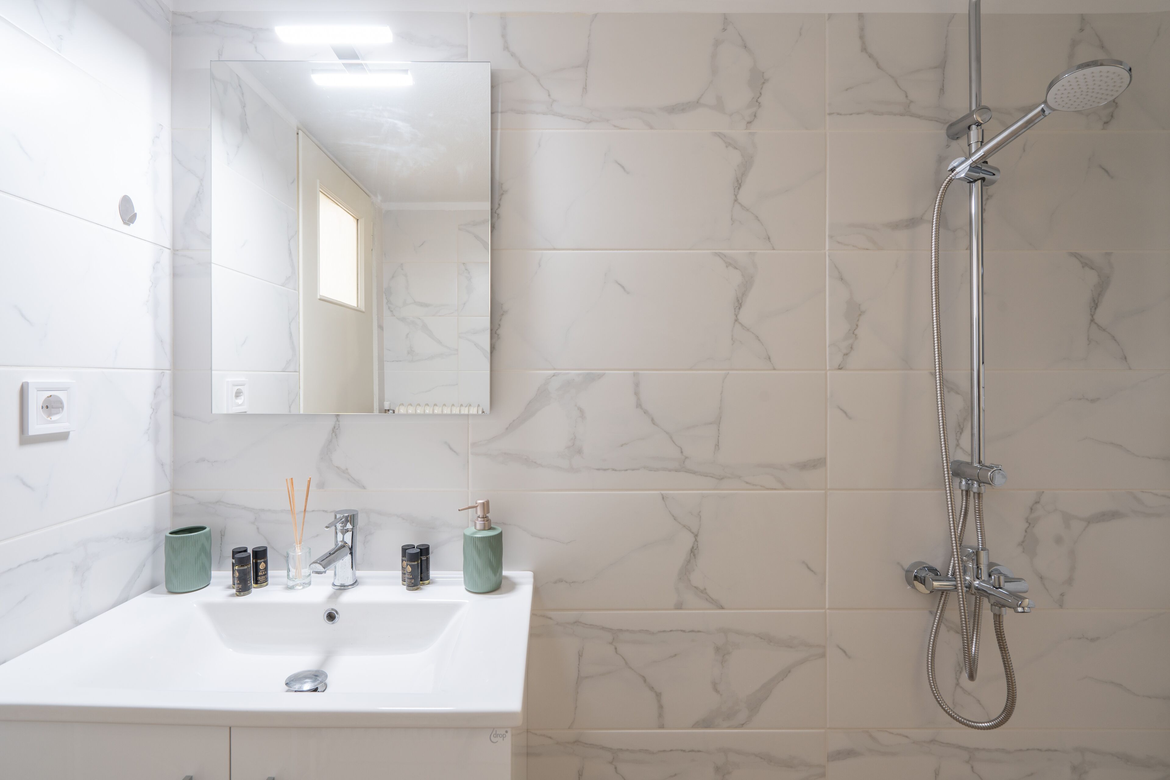 A bathroom with a white sink, a mirror, and a shower.