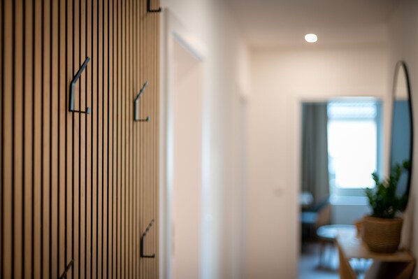A corridor with vertical wooden slats and a potted plant on a table. - SoWi: Design Apartment - Garden View & Parking (Kassel)