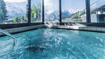 Piscina com vista para montanhas nevadas através de grandes janelas.