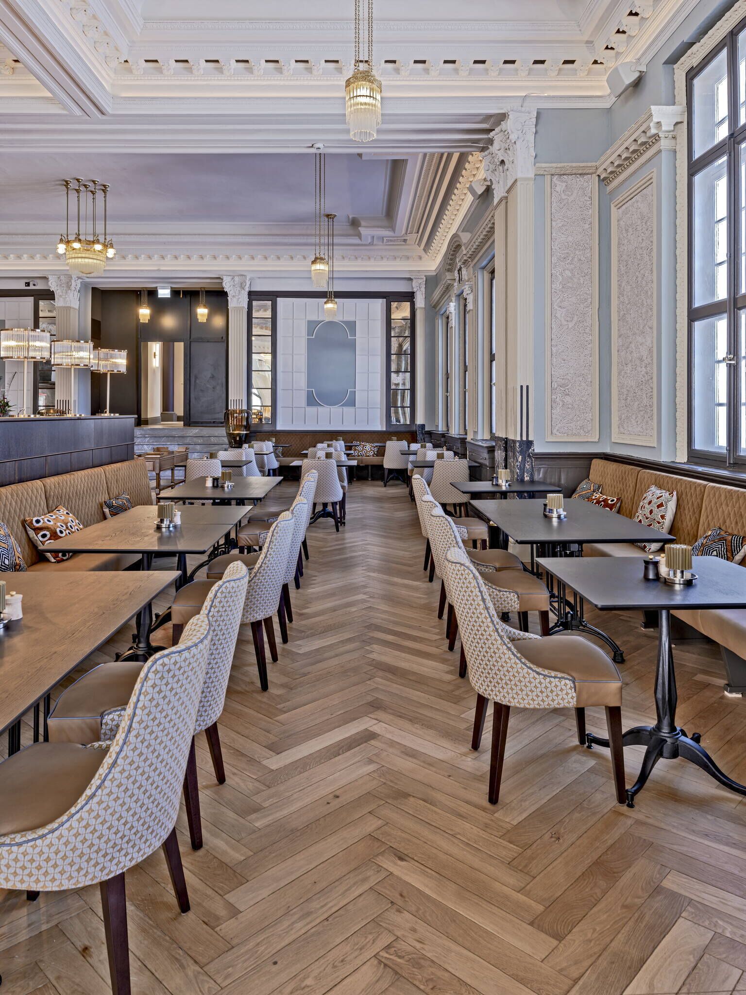 A spacious dining area with high ceilings, ornate moldings, and large windows.