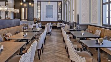 A spacious dining area with high ceilings, ornate moldings, and large windows.