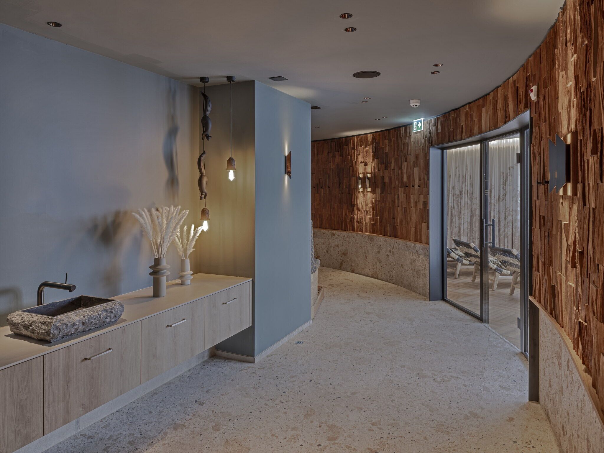 Une salle de bain moderne avec un lavabo en pierre, des panneaux muraux en bois et une cabine de douche en verre.