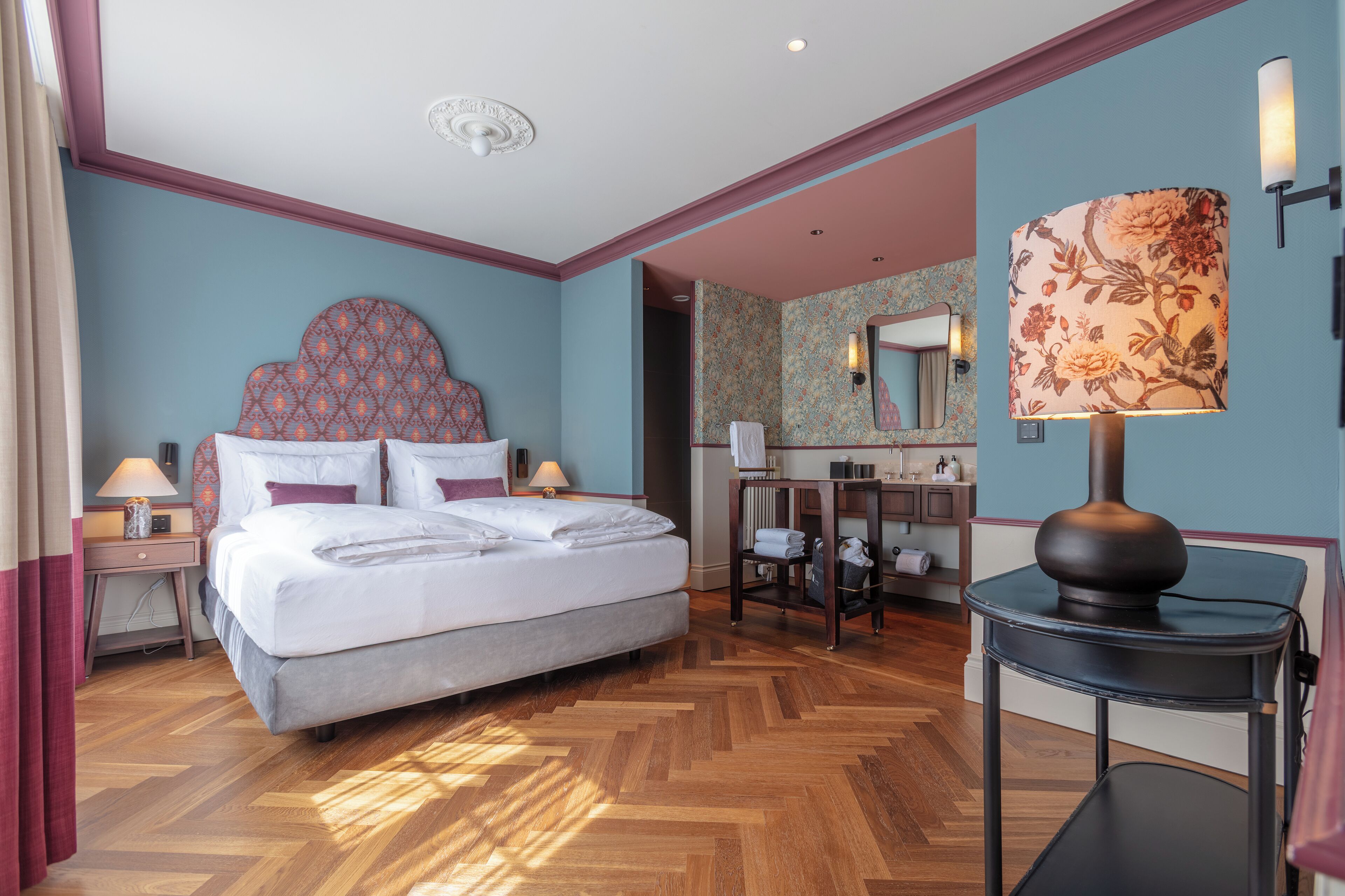 Ein Hotelzimmer mit einem großen Bett, einem Schreibtisch, einem Sessel, einer Lampe und einem Spiegel.