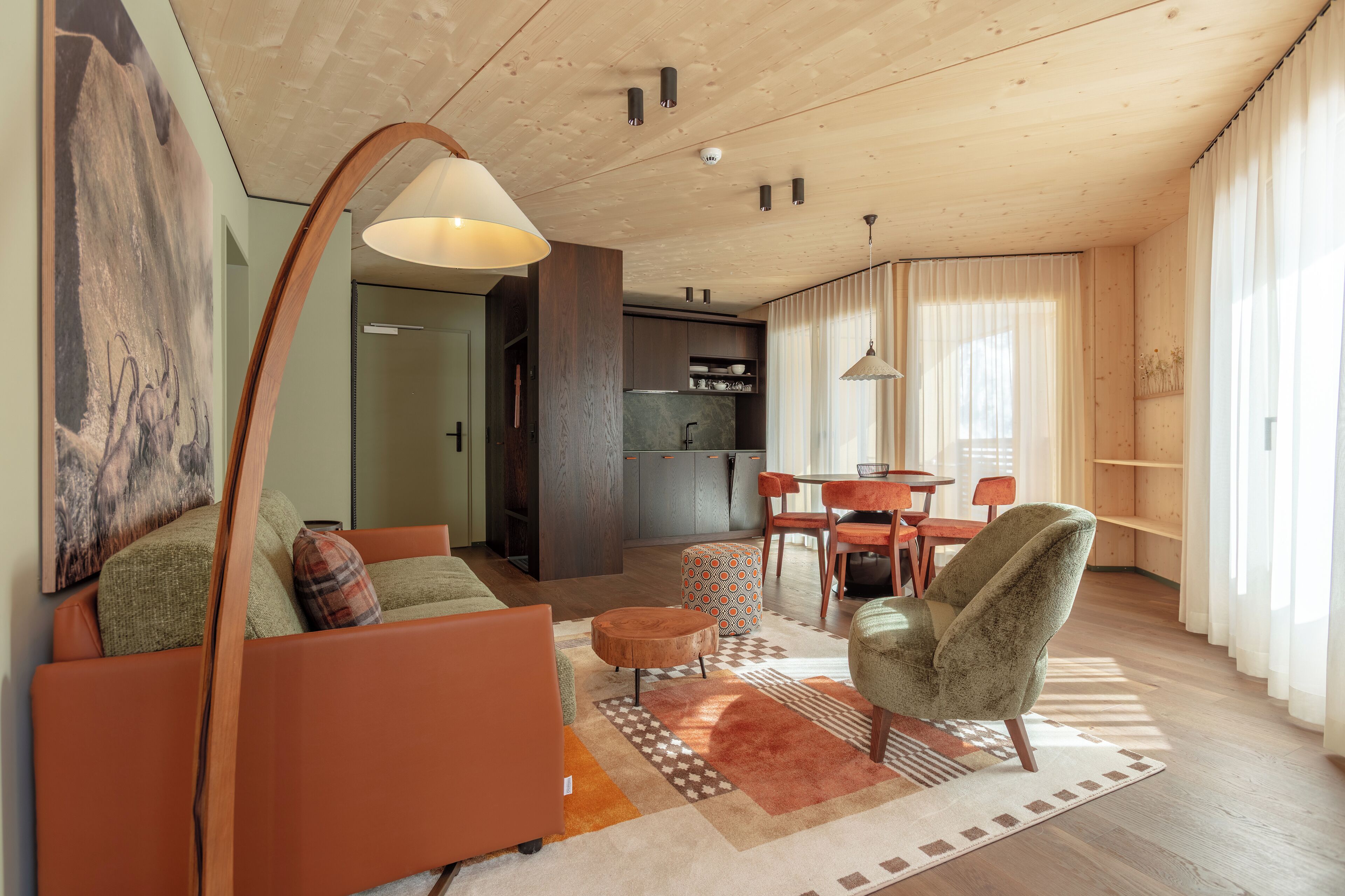 A modern living room with a sofa, armchair, ottoman, and a dining area with chairs and a table.