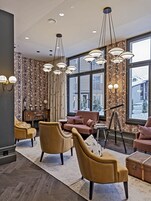 A modern lounge area with leather sofas, a telescope, and large windows offering a view of a snowy landscape.