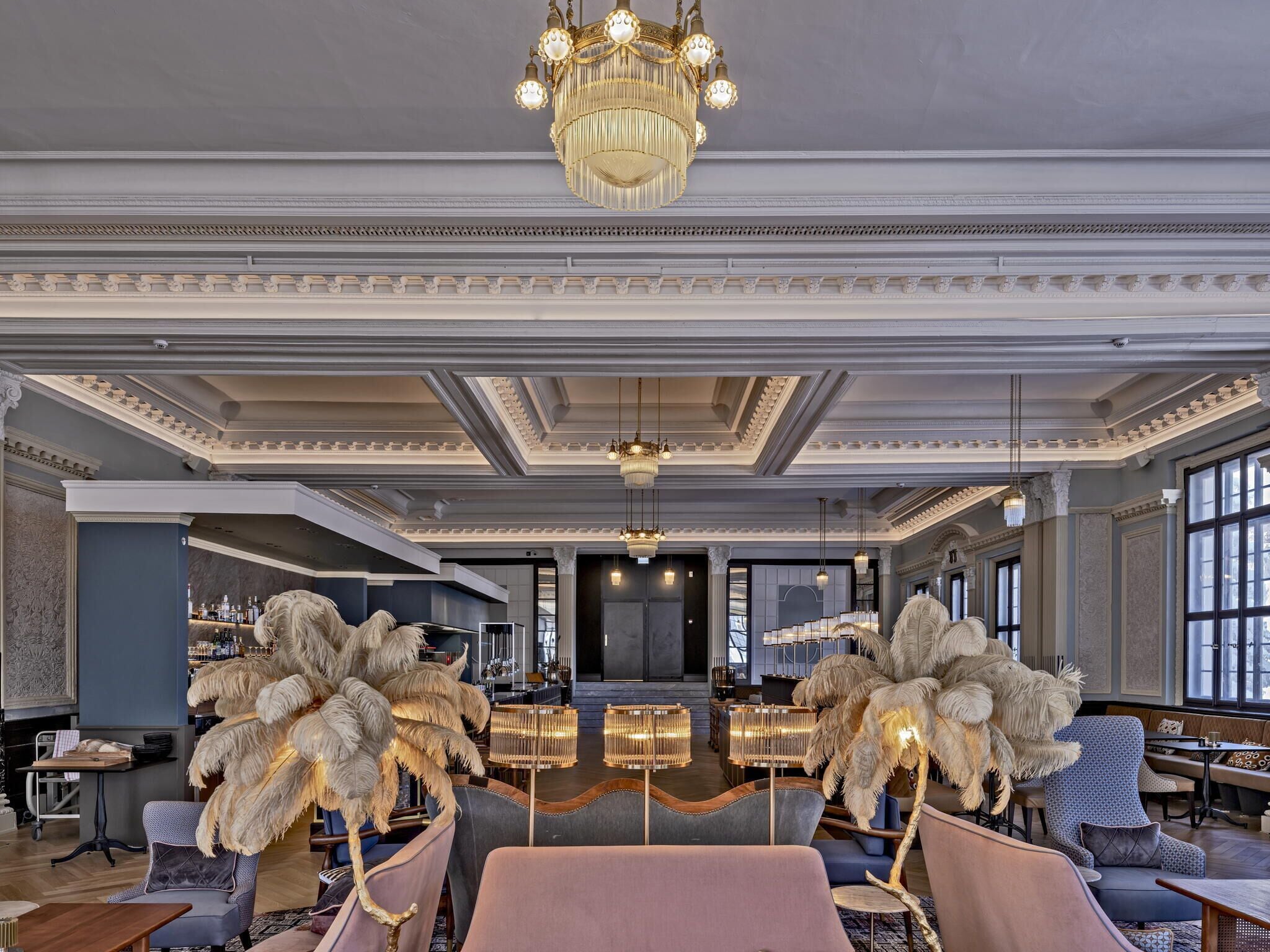 A luxurious lobby with ornate chandeliers, plush seating, and a grand staircase.