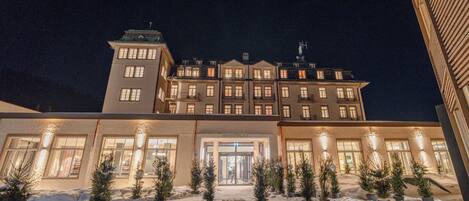 Un hotel grande de varios pisos con una entrada destacada y paisajes nevados.