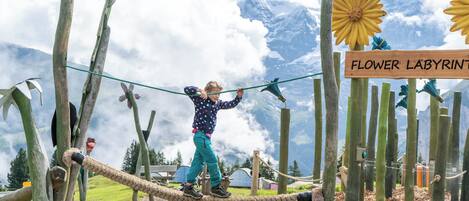 A rope bridge over a garden with a sign reading "Flower Labyrinth".