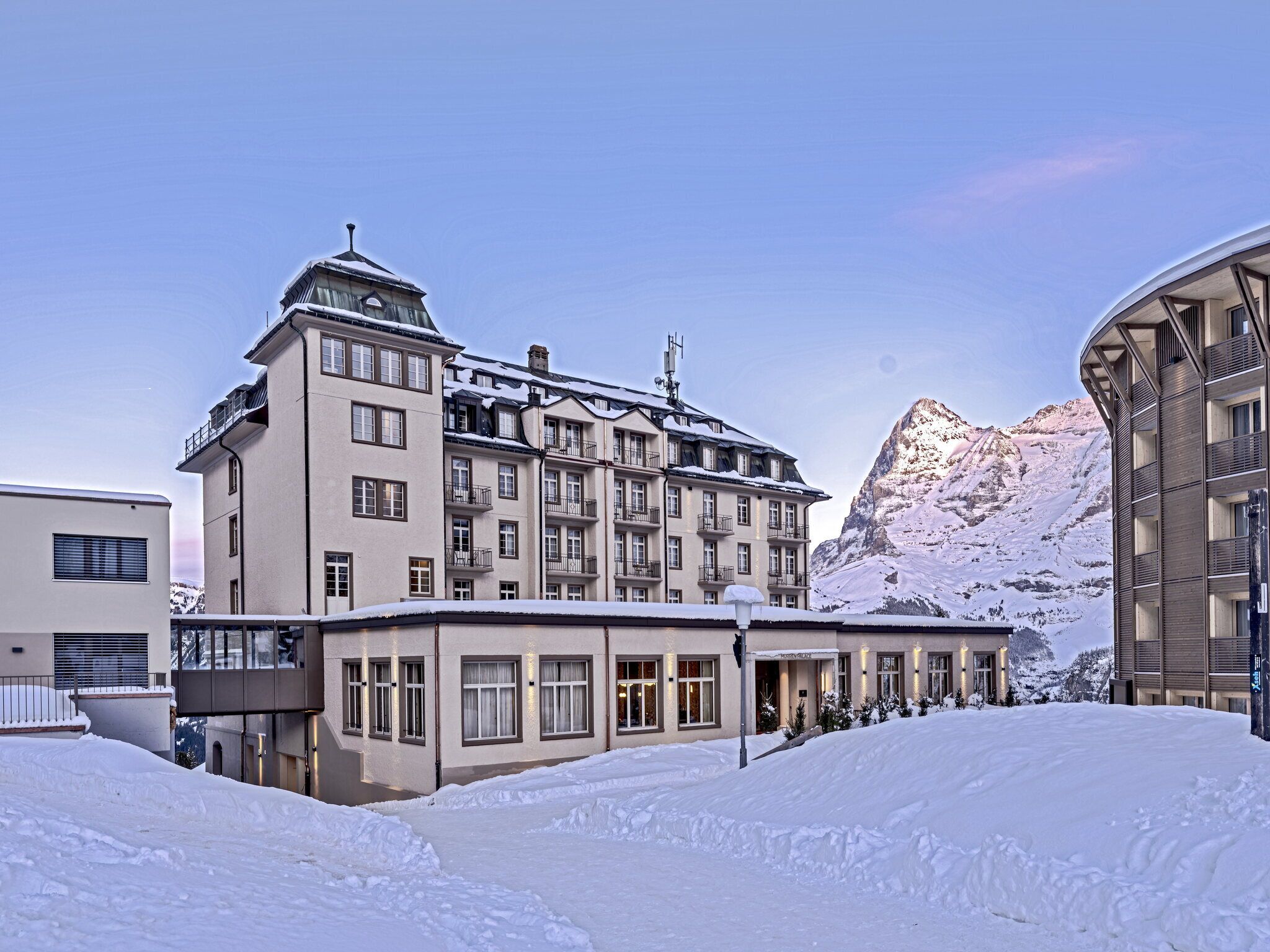 Un hôtel à plusieurs étages, doté de balcons et offrant une vue sur les montagnes.