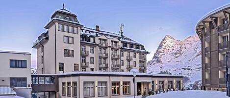 Un hôtel à plusieurs étages, doté de balcons et offrant une vue sur les montagnes.