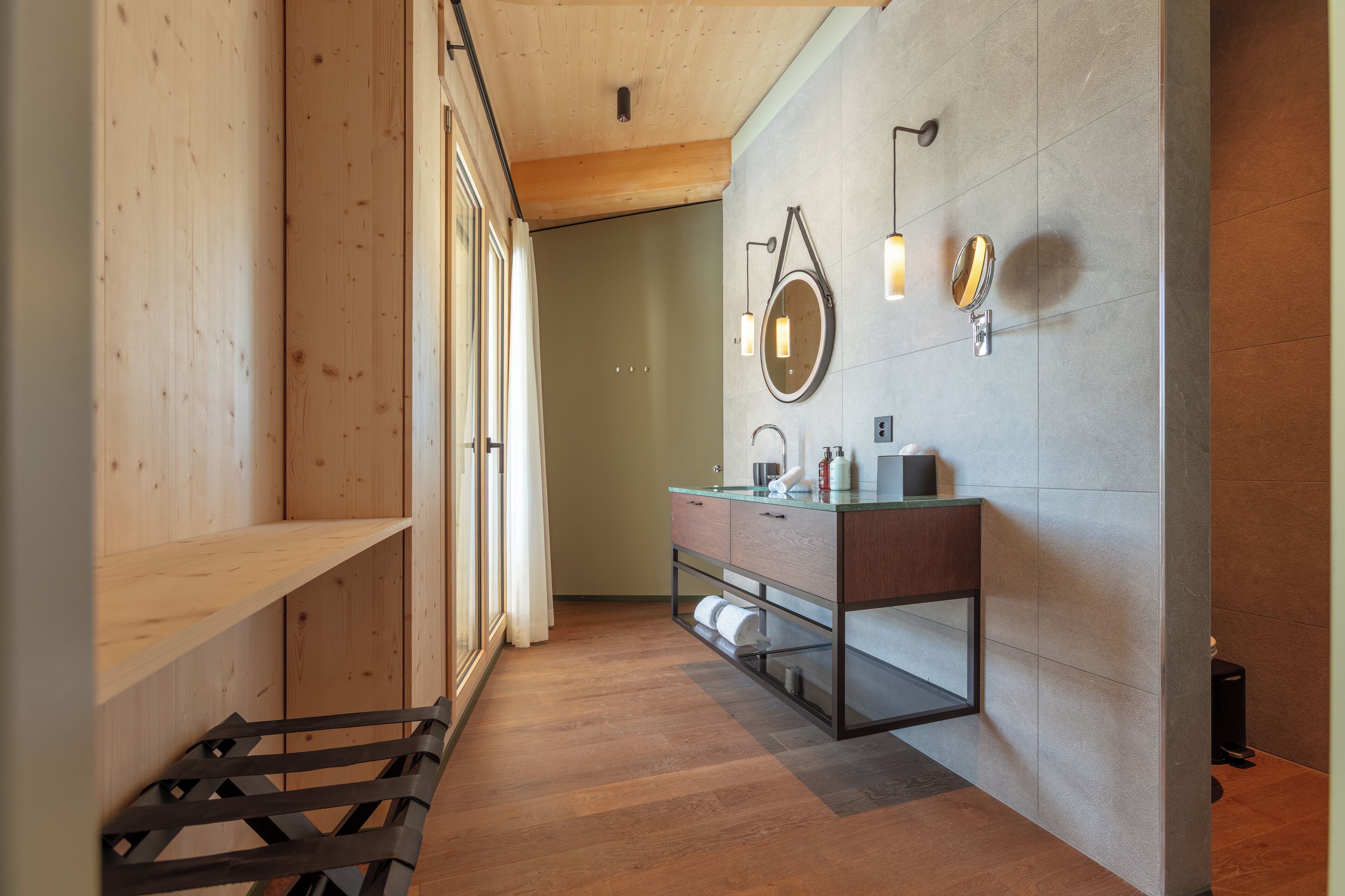 A modern bathroom with wooden flooring, a glass vanity, and a large mirror.