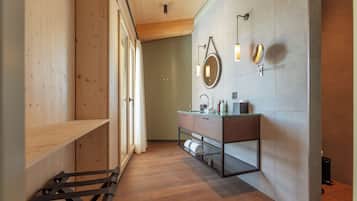 A modern bathroom with wooden flooring, a glass vanity, and a large mirror.