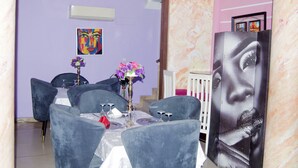 A dining area with a table set for six, surrounded by blue chairs, with a vase of flowers on the table.