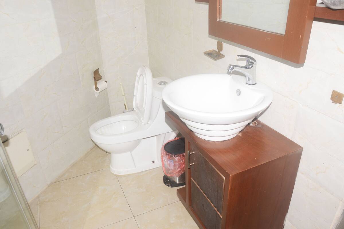 A bathroom with a toilet, sink, and mirror.