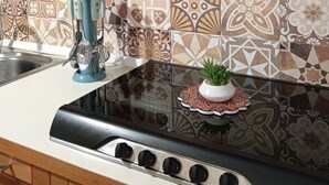 Una cocina con baldosas estampadas, una campana de cristal, una estufa con cuatro hornillas y una pequeña planta en la encimera.