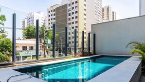 Une piscine rectangulaire aux carreaux bleu clair, entourée d’une terrasse également carrelée de blanc.