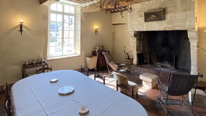 Ein Essbereich mit großem Tisch, Stühlen, Kamin und einer Kristallleuchter.