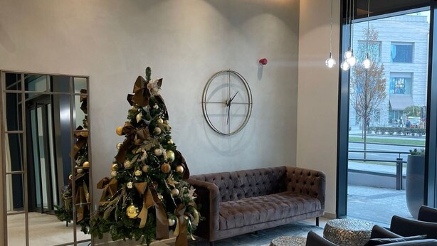 A modern lobby with a large Christmas tree, a round wall clock, and a sofa. - Belgrade Waterfront Tower View (Belgrade)