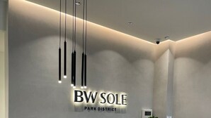 A reception desk with a marble top and a wooden base, a sign reading "BWV SOLE PARK DISTRICT", and pendant lighting. - Belgrade Waterfront Tower View (Belgrade)