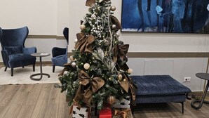 A modern living room with a Christmas tree, two blue armchairs, a small round table, and a large abstract painting on the wall. - Belgrade Waterfront Tower View (Belgrade)