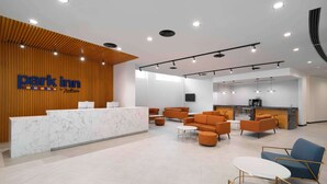 A modern hotel lobby with a reception desk, seating area, and a kitchenette. - Park Inn by Radisson Makkah Thakher Algharbi (Makkah)