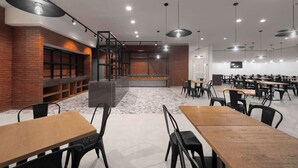 A modern dining area with brick walls, wooden tables, and black chairs. - Park Inn by Radisson Makkah Thakher Algharbi (Makkah)