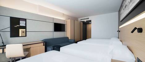 A modern hotel room with a large bed, a desk, a chair, and a sofa.