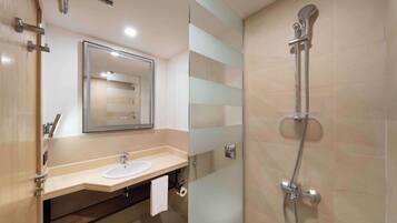 A modern bathroom with a glass shower enclosure, a sink with a mirror, and a towel hanging on the wall.