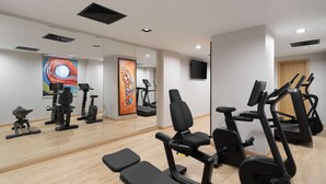 A modern gym with various exercise equipment, a large mirror, and a flat-screen TV on the wall. - Park Inn by Radisson Makkah Thakher Algharbi (Makkah)