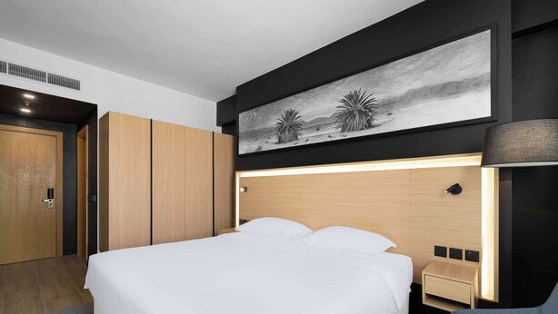 A modern hotel room with a large bed, wooden wardrobe, and a painting of desert plants. - Park Inn by Radisson Makkah Thakher Algharbi (Makkah)