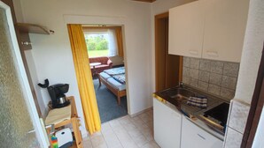 Cocina compacta con lavabo, estufa y comedor con mesa y sillas.