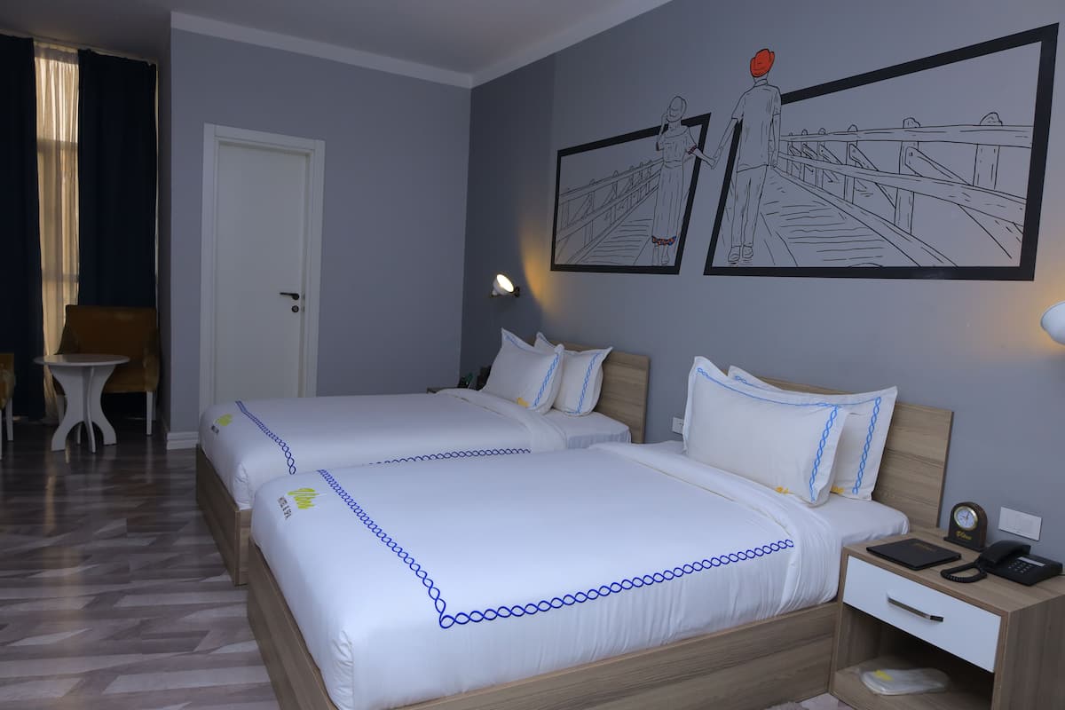 A hotel room with two beds, a nightstand, a chair, and artwork on the wall.