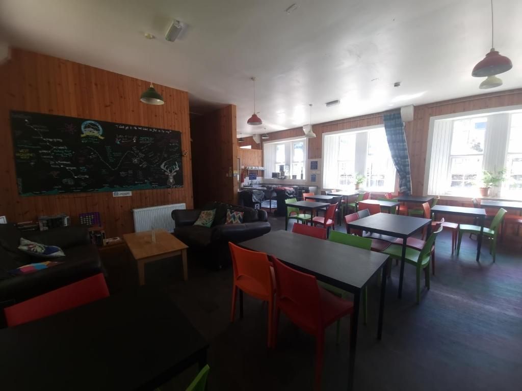 Un restaurante con un menú en pizarra, paredes de madera y una variedad de opciones de asientos, incluidas mesas y sillas.