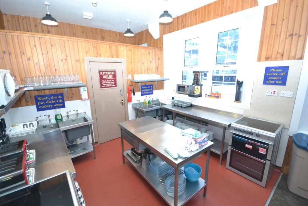Een keuken met roestvrijstalen apparatuur, een spoelbak en een bordje met regels voor de keuken.
