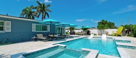 A swimming pool with multiple sections, lounge chairs, and umbrellas.