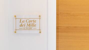 A sign with the text "La Corte dei Mille LUXURY" pinned to a white wall.