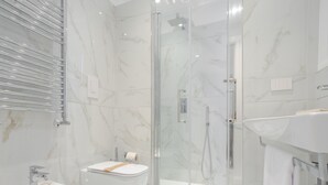 Un baño moderno con ducha envuelta en vidrio, un bidé y un lavamanos con espejo.